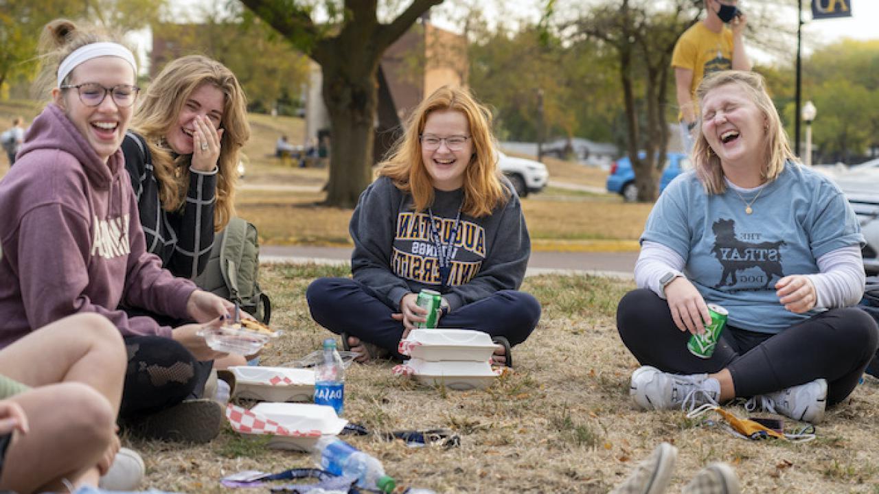 students laughing on the campus green